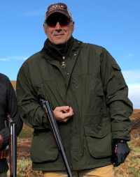 Roger N. Farah outside holding a shotgun